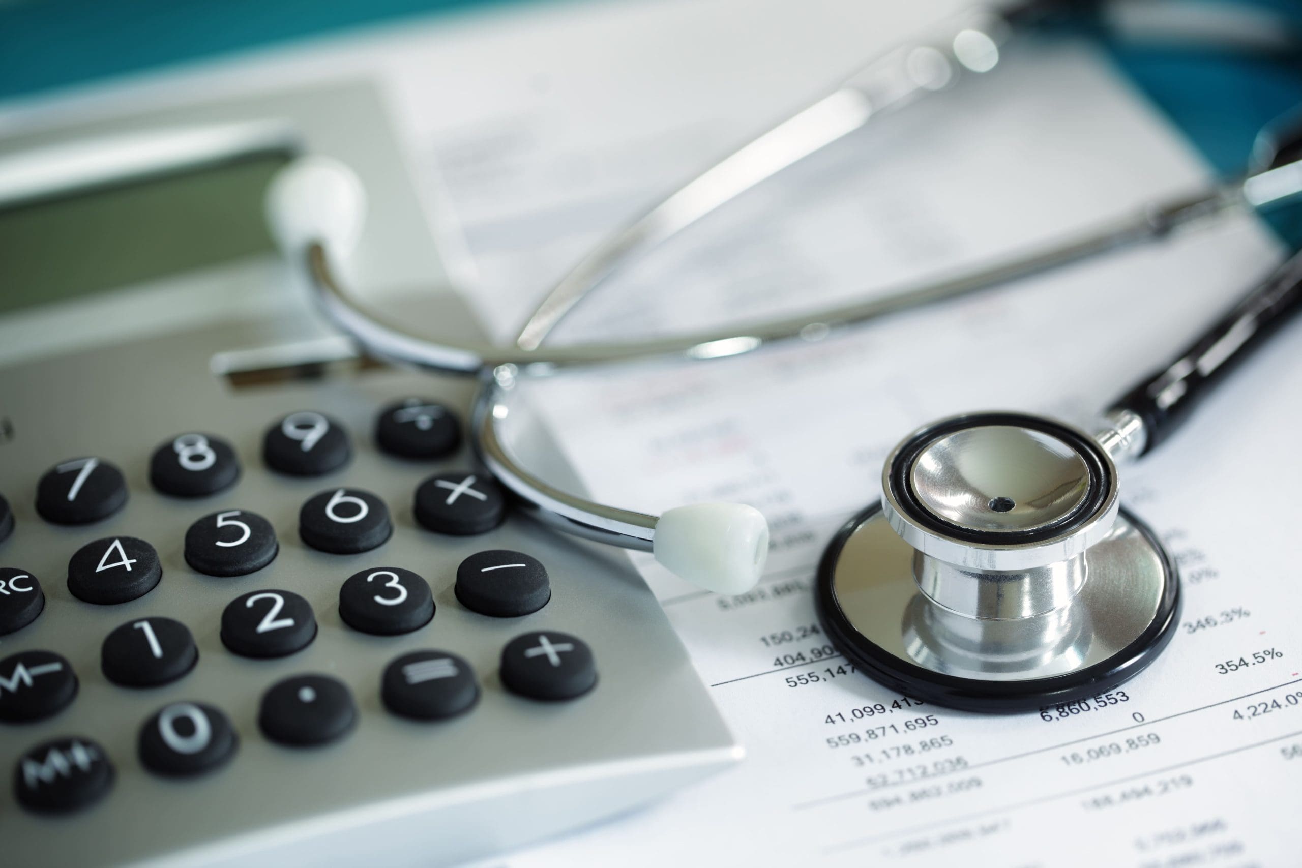 A stethoscope and calculator lay on top of a document.