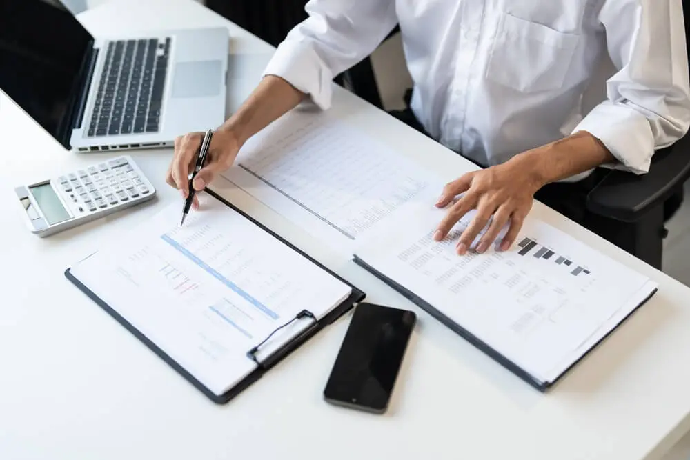 rd tax specialist calculating tax in an office setting, sat at a desk with a laptop, notebook, and calculator