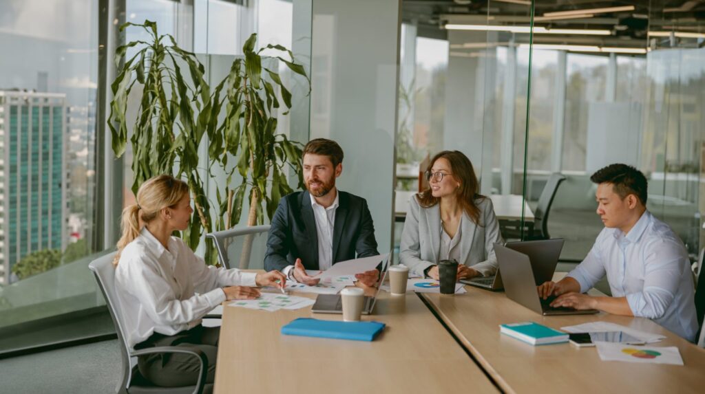 a mix of male and female colleagues sat together at a desk in a corporate setting