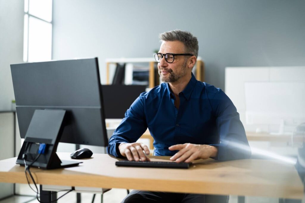 male office worker sat at a desk in a professional setting