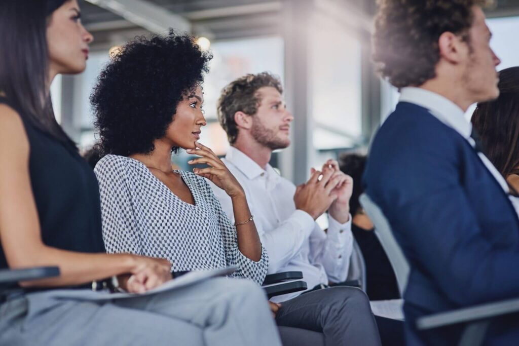 two female and two male colleagues sat in the audience of a business conference 